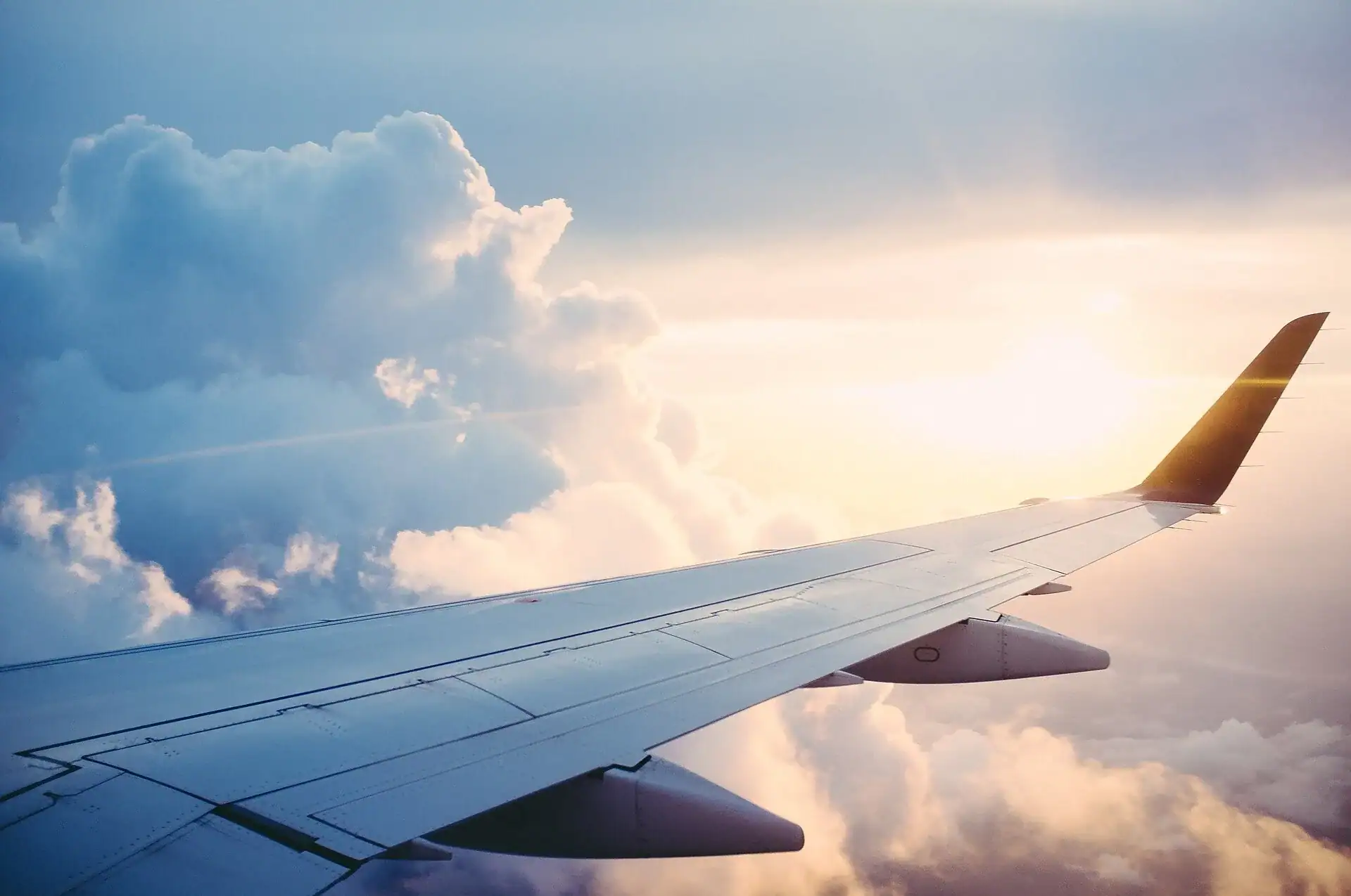 An airplane wing tip seen from the window above the clouds